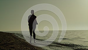 Silhouette woman running beach at sunset. Girl jogging seacoast summer evening.