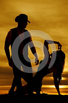 Silhouette of a woman sitting on heel looking up at cowboy
