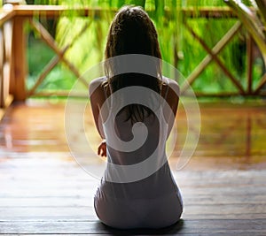 silhouette of a woman sitting on the porch during the rain.