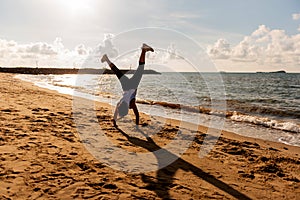 Silhouette woman somersault and exercise on the beach sunset.