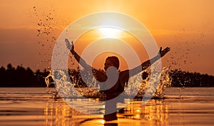 Woman splashing water in infinity pool at sunset