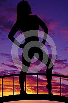 Silhouette of woman stand hands on hips knee out