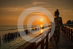 Silhouette of a woman standing on a bridge with a sunset behind