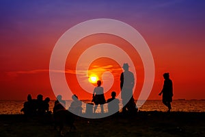 silhouette woman standing with family looking sunset on beach