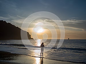 Silhouette of woman standing in front of sunet reflection on the