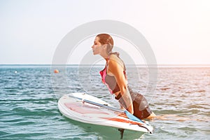 Sea woman sup. Silhouette of happy young woman in pink bikini, surfing on SUP board, confident paddling through water