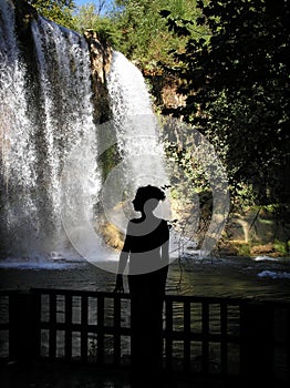 Silhouette of woman standing by waterfall photo