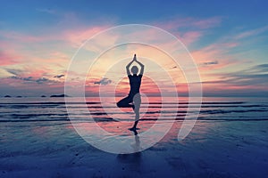 Silhouette of woman standing at yoga pose on the beach