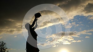 Silhouette of Woman student throwing her hat in slow motion at sunset.