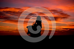 Silhouette of a woman in sunset with dress and hair blow by the wind