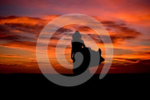 Silhouette of a woman in sunset with dress and hair blow by the wind