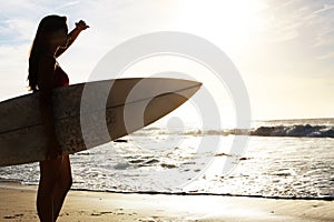 Silhouette, woman surfer on beach with sea and exercise outdoor with surfboard to surf in nature. Sport, shadow and sun