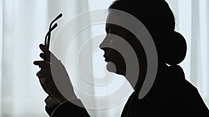 Silhouette of woman taking off glasses, suffering eye strain, fatigue at work