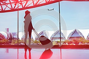 Silhouette woman travel with luggage looking without window at airport