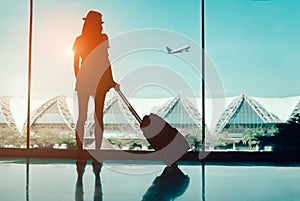Silhouette woman travel with luggage looking without window at airport terminal international or girl teenager traveling in vacati photo