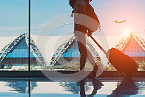 Silhouette woman travel with luggage walking side window at airport terminal international