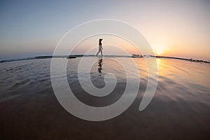 silhouette of a woman walking along the seashore. Spiritual Peace Meditation. A happy girl walks along the seashore against the