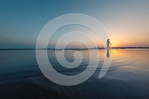 silhouette of a woman walking along the seashore. Spiritual Peace Meditation. A happy girl walks along the seashore against the