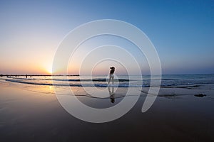 silhouette of a woman walking along the seashore. Spiritual Peace Meditation. A happy girl walks along the seashore against the