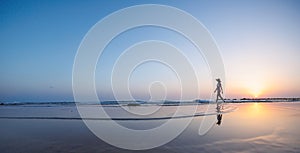 silhouette of a woman walking along the seashore. Spiritual Peace Meditation. A happy girl walks along the seashore against the