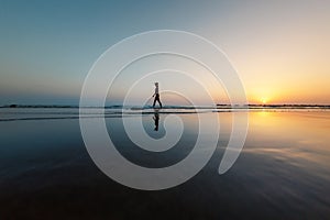 silhouette of a woman walking along the seashore. Spiritual Peace Meditation. A happy girl walks along the seashore against the