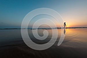 silhouette of a woman walking along the seashore. Spiritual Peace Meditation. A happy girl walks along the seashore against the