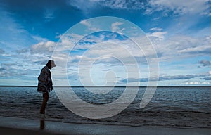 Silhouette woman walking on seabeach in evening with beautiful blue sky over sea water, look lonely and quiet.