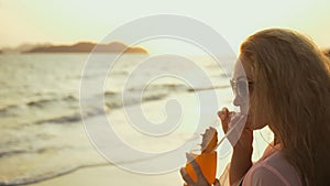 Silhouette woman walks on sunset on beach against background of