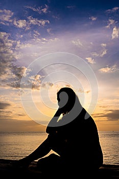 Silhouette of a woman watching colorful sunrise over the ocean