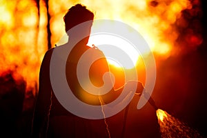 Silhouette of a woman watering grass at sunset