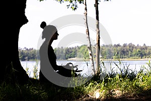 silhouette of a woman who practices yoga and meditates in the lotus position in nature