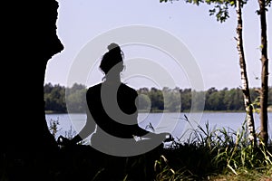 silhouette of a woman who practices yoga and meditates in the lotus position in nature