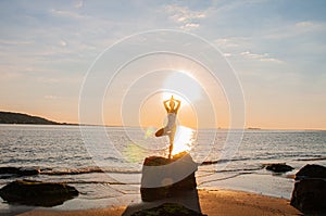 Silhouette woman yoga on the beach at sunrise. Woman is practicing yoga at sunset on sea shore