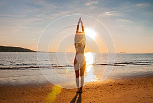 Silhouette woman yoga on the beach at sunrise. Woman is practicing yoga at sunset on sea shore