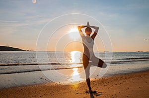 Silhouette woman yoga on the beach at sunrise. Woman is practicing yoga at sunset on sea shore