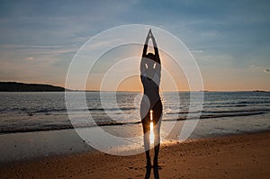 Silhouette woman yoga on the beach at sunset. Woman is practicing yoga at sunset on sea shore