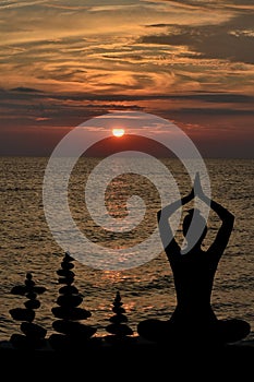 Silhouette of woman in yoga posture and balanced stones