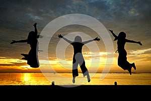 Silhouette of women jumping at the sea