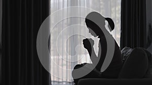 Silhouette of a women is praying to God in the morning room. Praying hands with faith in religion and belief in God on blessing