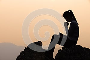 Silhouette of a women is praying to God on the mountain. Praying hands with faith in religion and belief in God on blessing