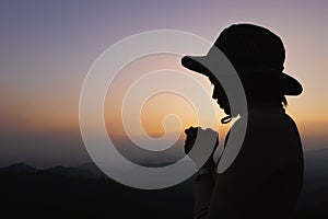 Silhouette of a women is praying to God on the mountain. Praying hands with faith in religion and belief in God on blessing