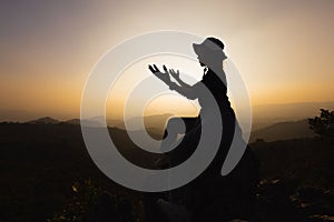 Silhouette of a women is praying to God on the mountain. Praying hands with faith in religion and belief in God on blessing