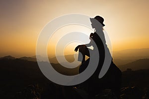 Silhouette of a women is praying to God on the mountain. Praying hands with faith in religion and belief in God on blessing