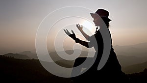 Silhouette of a women is praying to God on the mountain. Praying hands with faith in religion and belief in God on blessing