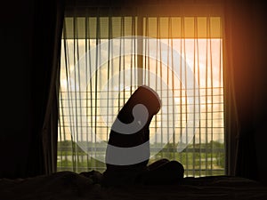 Silhouette women sadness alone sitting on the bed with the widows in the morning