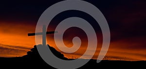 The silhouette of wooden cross on fiery sky background