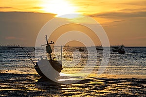 Silhouette wooden fishing boat on beach at sunset, Sriracha