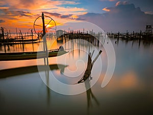 Silhouette wooden posts in lake against orange sky