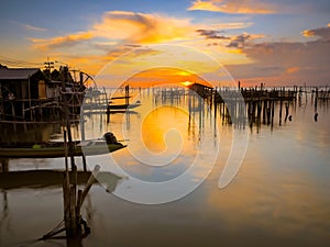 Silhouette wooden posts in lake against orange sky at Songkhla Thailand