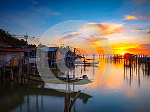 Silhouette wooden posts in lake against orange sky at Songkhla Thailand